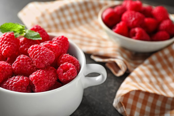 Pot with sweet ripe raspberries on table, closeup