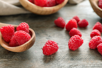 Wooden spoon with sweet ripe raspberries on table, closeup