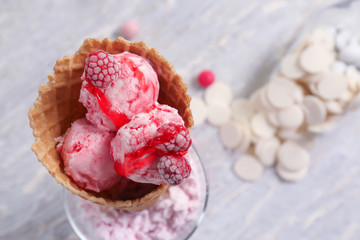 Waffle cone with delicious raspberry ice-cream on table, closeup