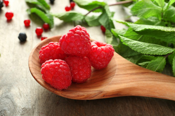 Wooden spoon with delicious fresh raspberries on table