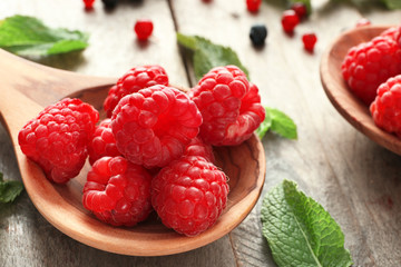 Wooden spoon with delicious fresh raspberries on table, closeup