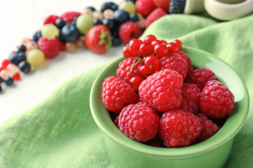 Bowl with delicious raspberries and red currant on table, closeup