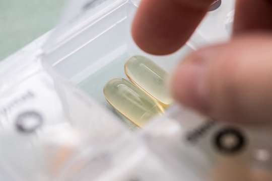 Frau nimmt Pillen aus Pillendose Wochendispenser zur Therapie 