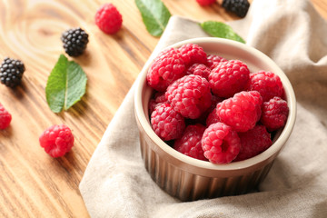 Bowl with delicious raspberries on wooden table