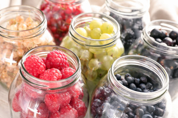 Fototapeta na wymiar Glass jars with delicious ripe berries on table