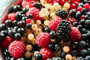 Assortment of fresh ripe berries in colander, closeup