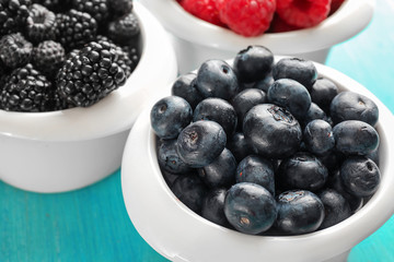 Bowls with delicious ripe blueberries on table, closeup