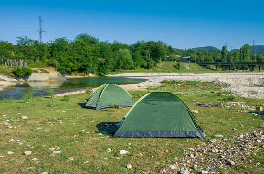 The camping tents near mountain river in the summer
