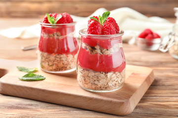 Delicious dessert with raspberries in glass jars on wooden table