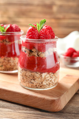 Delicious dessert with raspberries in glass jars on wooden table