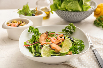 Tasty salad with seafood and green vegetables in bowl on table