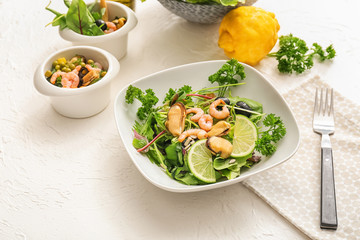 Tasty salad with seafood and green vegetables in bowl on table