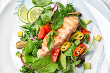 Tasty fish and fresh salad on plate, closeup