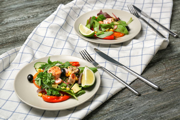 Plates with tasty fresh salad on wooden table