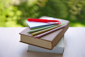 books, school supplies on a table on a natural green background, the concept of education