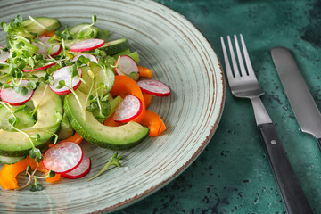 Plate with fresh vegetable salad on color textured background