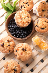 Tasty blueberry muffins with fresh berries and honey on table