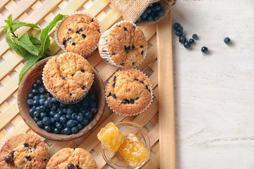 Tasty blueberry muffins with fresh berries and honey on table