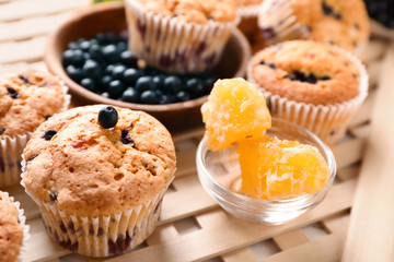 Tasty blueberry muffins with honey on table