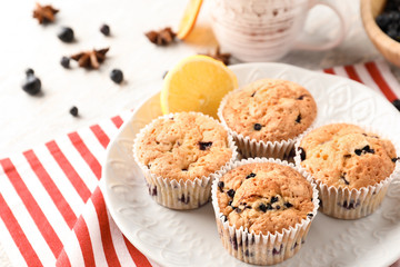 Plate with tasty blueberry muffins on table