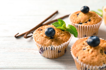 Tasty blueberry muffins on light wooden background