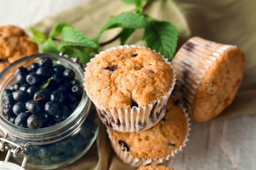 Tasty blueberry muffins and glass jar with fresh berries on table, closeup