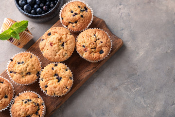 Wooden board with tasty blueberry muffins on table