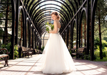 Obraz premium Beautiful young bride with wedding bouquet outdoors