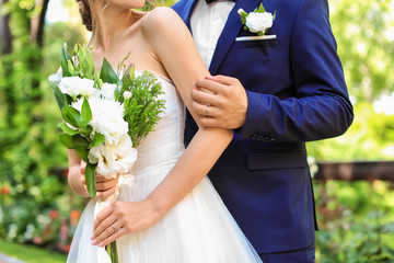 Happy newlyweds with beautiful wedding bouquet outdoors