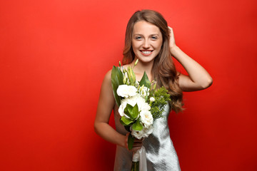 Young woman with beautiful flowers on color background