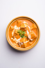 Paneer Butter Masala also known as Panir  makhani or makhanwala. served in a ceramic or terracotta bowl with fresh cream and coriander. Isolated over colourful moody background. selective focus