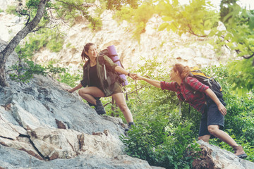 Group Hiker woman helping her friend climb up the last section of sunset in mountains. Traveler...