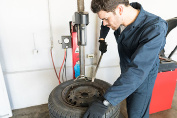 Repairman Removing Tire From Rim On Machine At Garage