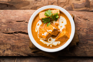 Paneer Butter Masala also known as Panir  makhani or makhanwala. served in a ceramic or terracotta bowl with fresh cream and coriander. Isolated over colourful moody background. selective focus