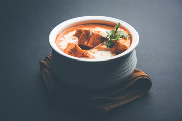 Paneer Butter Masala also known as Panir  makhani or makhanwala. served in a ceramic or terracotta bowl with fresh cream and coriander. Isolated over colourful moody background. selective focus
