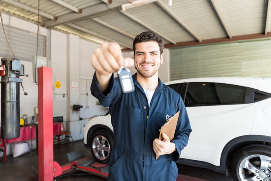 Smiling Mechanic Giving Car Key In Auto Repair Shop