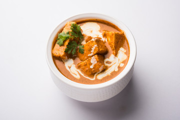 Paneer Butter Masala also known as Panir  makhani or makhanwala. served in a ceramic or terracotta bowl with fresh cream and coriander. Isolated over colourful moody background. selective focus
