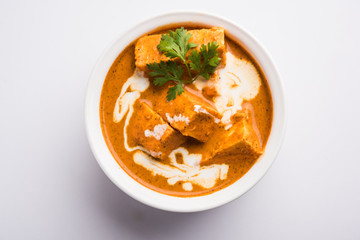 Paneer Butter Masala also known as Panir  makhani or makhanwala. served in a ceramic or terracotta bowl with fresh cream and coriander. Isolated over colourful moody background. selective focus