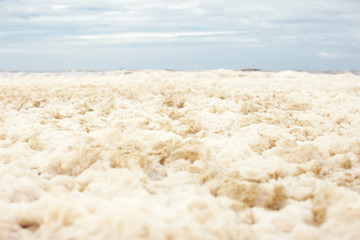 Fototapeta na wymiar sea and skies and a beach covered in sea foam