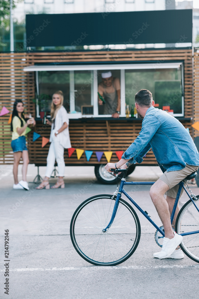 Wall mural side view of man sitting on bike near food truck