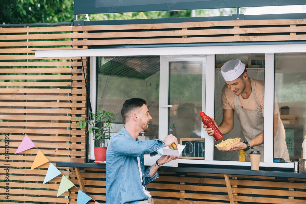 Sticker chef giving hot dog and ketchup to customer from food truck