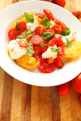 Heirloom tomatoes, burrito cheese and fresh basil leaves are seasoned with black pepper with copy space