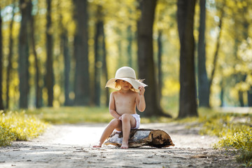 Young beautiful toddler girl sitting on a wooden log