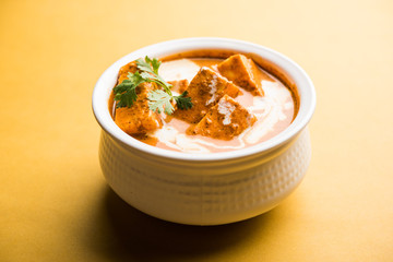 Paneer Butter Masala also known as Panir  makhani or makhanwala. served in a ceramic or terracotta bowl with fresh cream and coriander. Isolated over colourful moody background. selective focus