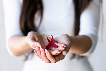 Woman holding red ribbon on her palms. AIDS awareness symbol