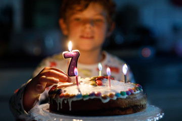 Adorable happy blond little kid boy celebrating his 7 birthday.