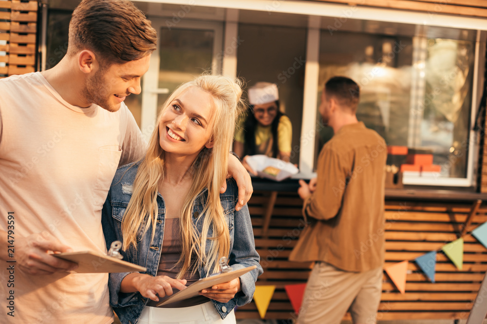 Sticker smiling couple holding menu near food truck