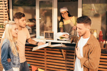 customer grimacing and rejecting burger from chef in food truck