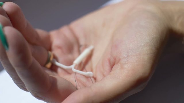 Woman showing a birth control device (IUD) in her palm. 
