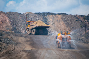 Heavy truck pours the road with water in the iron ore quarry. Dust removal, protection of the...